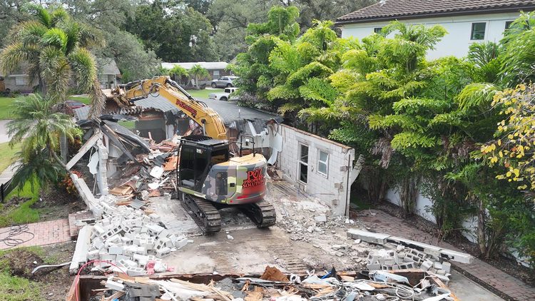 Excavator tearing down the walls and roof of an older house on Davis Islands, Tampa