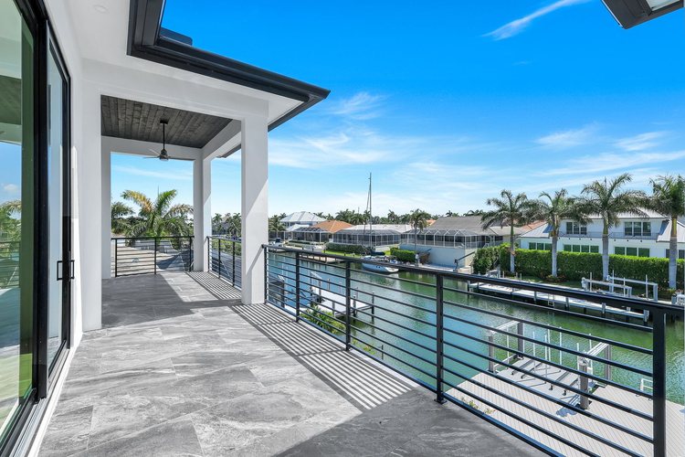 Covered upper balcony with horizontal railings overlooking a Marco Island canal and private dock