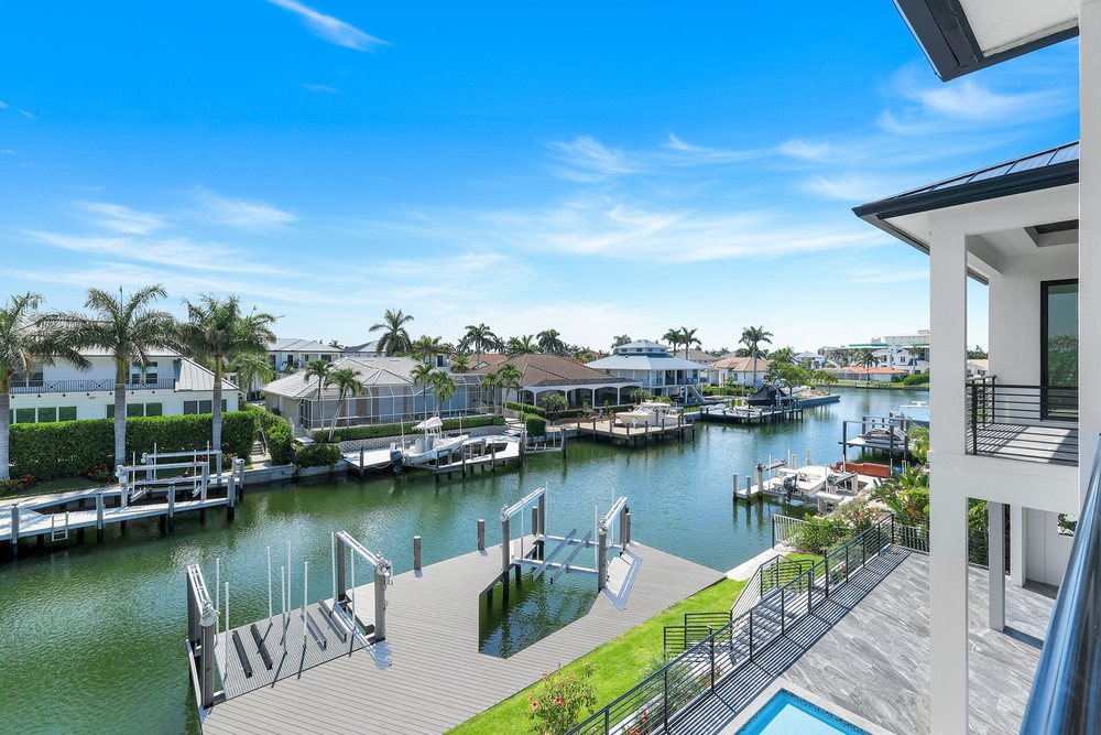 New composite dock with a boat lift on a Marco Island canal, seen from the upper balcony of a custom home
